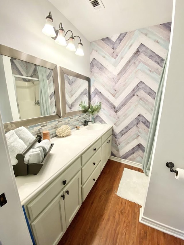 bathroom featuring hardwood / wood-style flooring, vanity, a shower, and tasteful backsplash