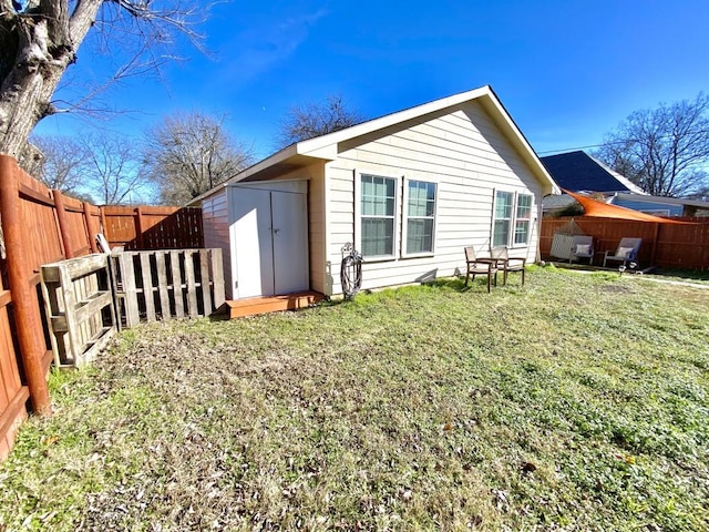 back of house featuring a lawn and a storage unit