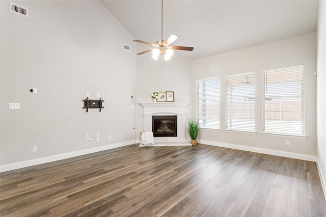 unfurnished living room with ceiling fan, dark hardwood / wood-style floors, and high vaulted ceiling