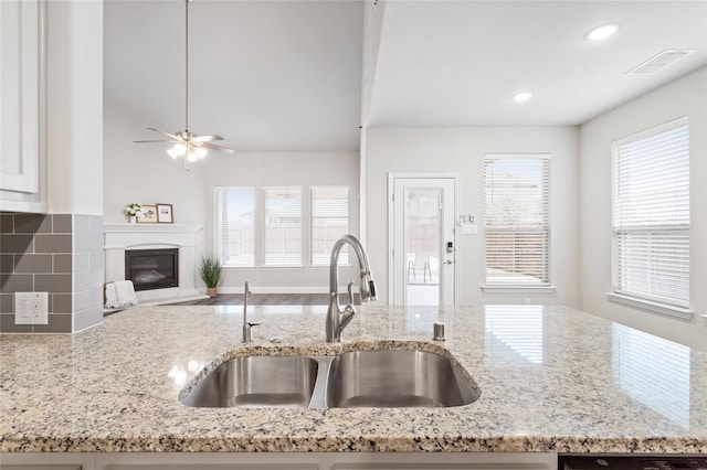 kitchen featuring sink, decorative backsplash, and light stone countertops