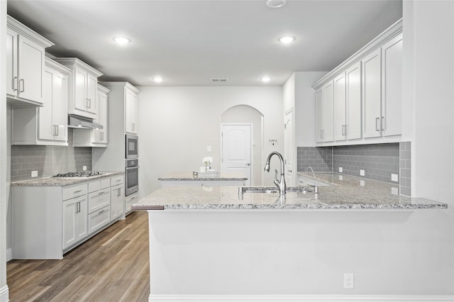 kitchen with stainless steel appliances, kitchen peninsula, sink, and white cabinets