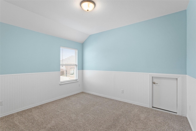 carpeted spare room with vaulted ceiling