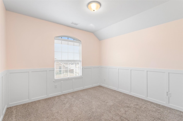 carpeted empty room with vaulted ceiling