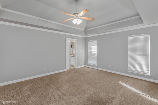 carpeted empty room with a raised ceiling, crown molding, vaulted ceiling, and ceiling fan