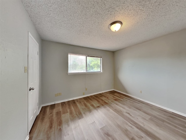 empty room featuring light hardwood / wood-style floors and a textured ceiling