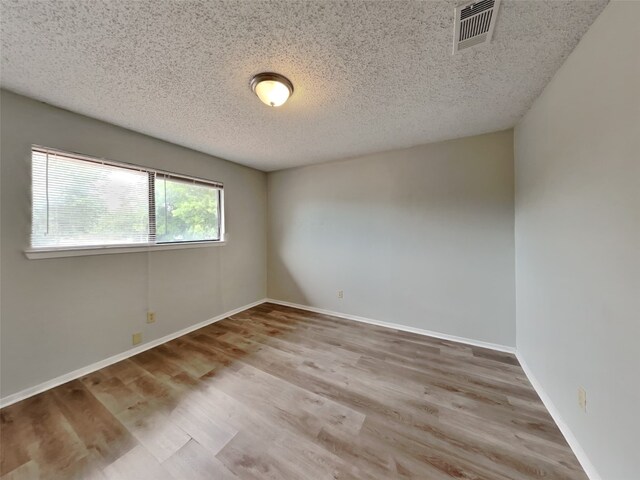 spare room with light hardwood / wood-style flooring and a textured ceiling