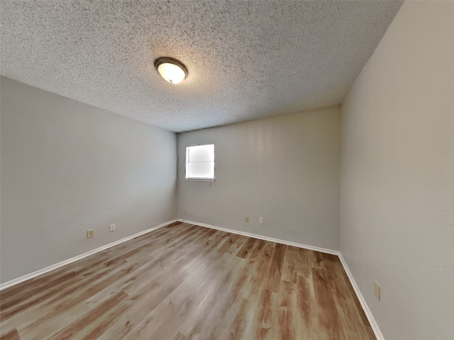 unfurnished room with a textured ceiling and light wood-type flooring