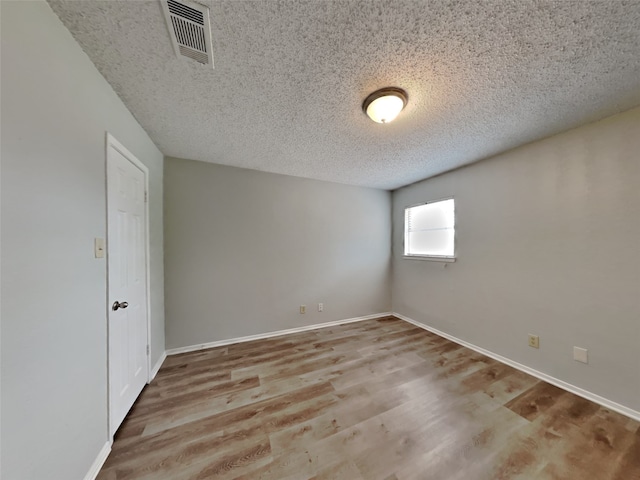 empty room with a textured ceiling and light wood-type flooring