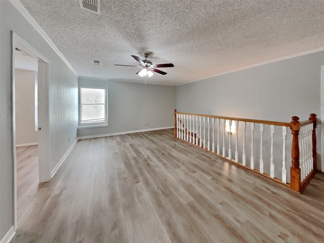 spare room featuring ceiling fan, light hardwood / wood-style flooring, ornamental molding, and a textured ceiling