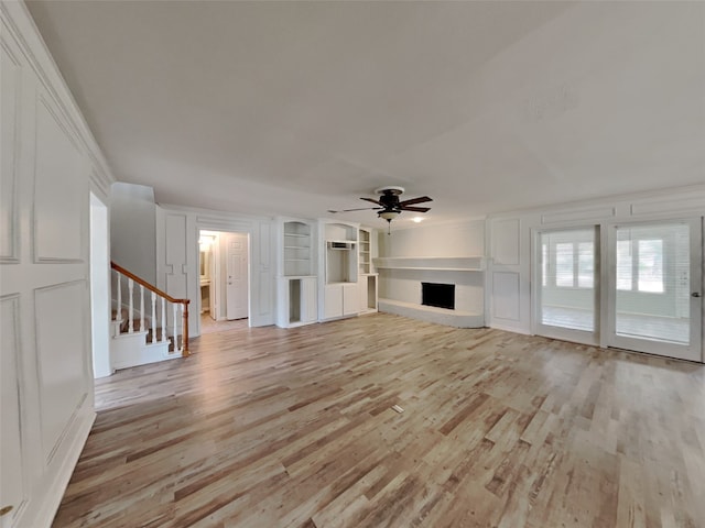 unfurnished living room featuring ceiling fan, built in features, and light wood-type flooring