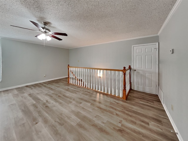 spare room featuring ceiling fan, ornamental molding, light hardwood / wood-style floors, and a textured ceiling