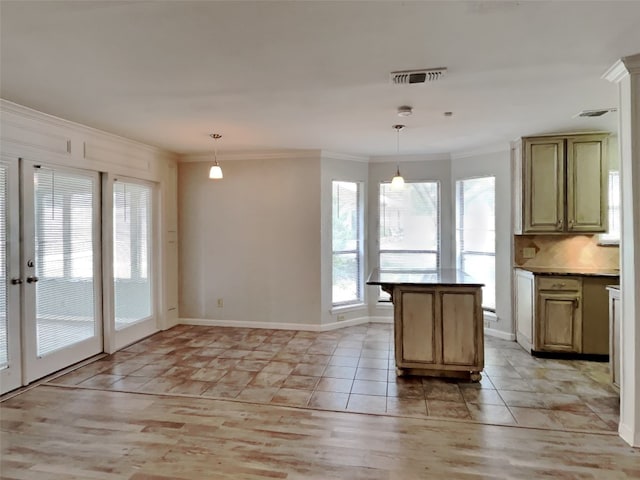 kitchen with decorative light fixtures, plenty of natural light, ornamental molding, and decorative backsplash