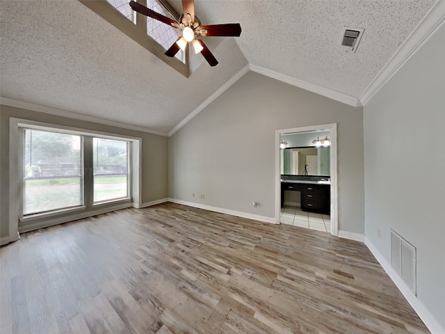 unfurnished living room with lofted ceiling, ornamental molding, a textured ceiling, and light wood-type flooring