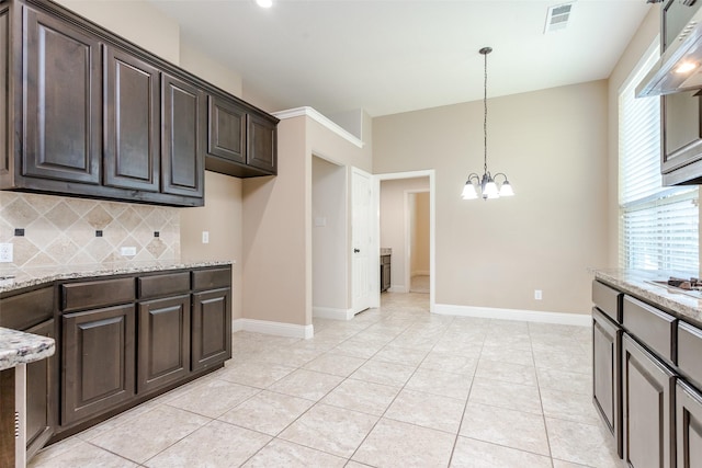 kitchen with dark brown cabinetry, light stone counters, an inviting chandelier, pendant lighting, and decorative backsplash