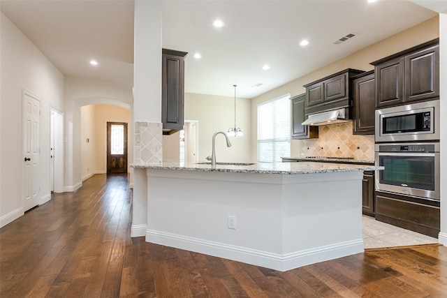 kitchen featuring sink, appliances with stainless steel finishes, light stone counters, light hardwood / wood-style floors, and kitchen peninsula