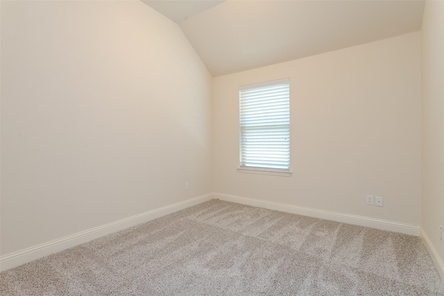 carpeted spare room with vaulted ceiling