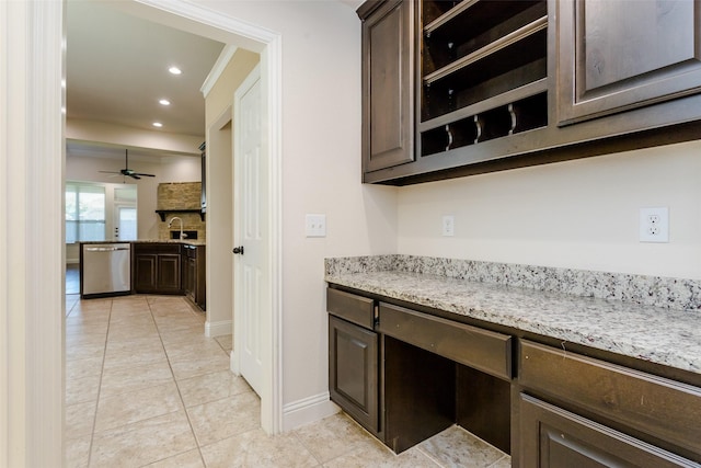 kitchen featuring light stone countertops, dishwasher, sink, and dark brown cabinets