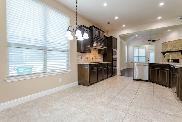 kitchen with pendant lighting, sink, appliances with stainless steel finishes, backsplash, and light stone countertops