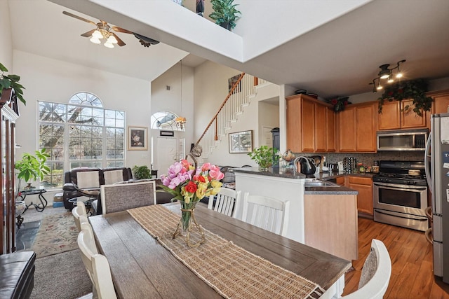 dining area with sink, hardwood / wood-style floors, ceiling fan, and a high ceiling