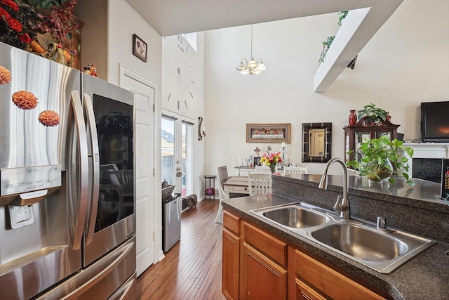 kitchen with sink, a chandelier, dark hardwood / wood-style floors, stainless steel fridge, and pendant lighting