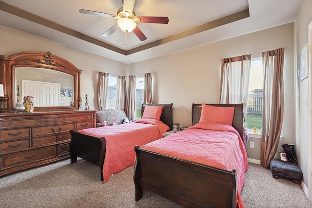 carpeted bedroom featuring a raised ceiling and multiple windows