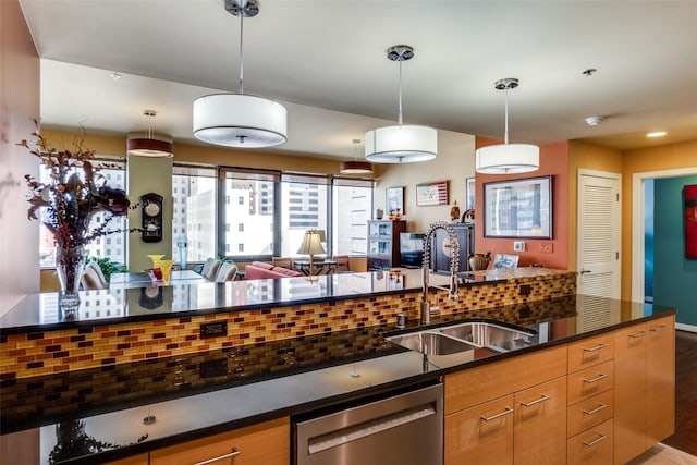 kitchen with pendant lighting, stainless steel dishwasher, sink, and decorative backsplash