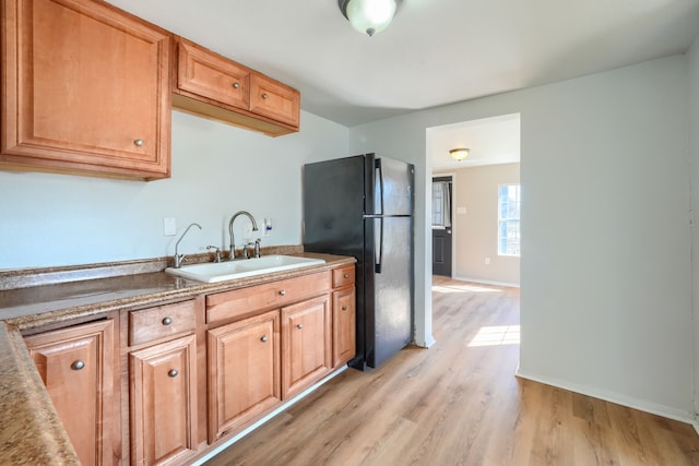 kitchen with sink, light wood-type flooring, and black fridge