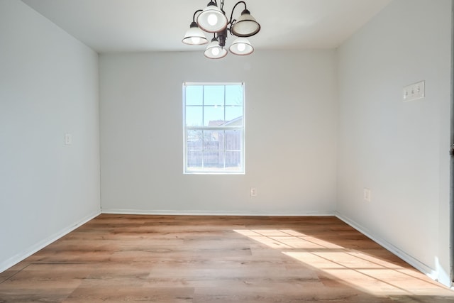 empty room featuring an inviting chandelier and light hardwood / wood-style floors