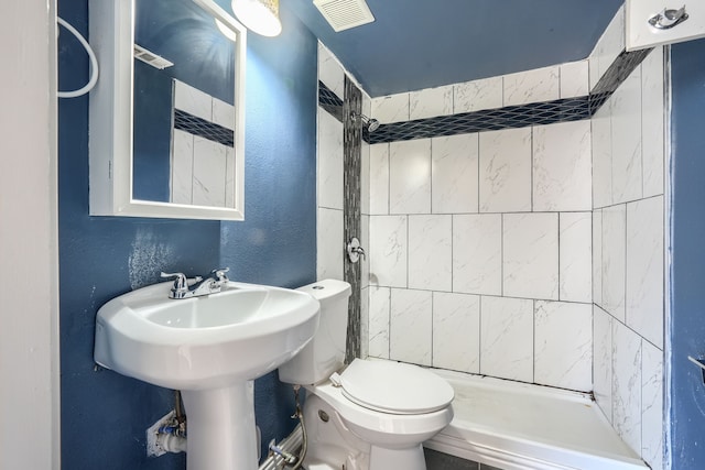 bathroom featuring tiled shower and toilet