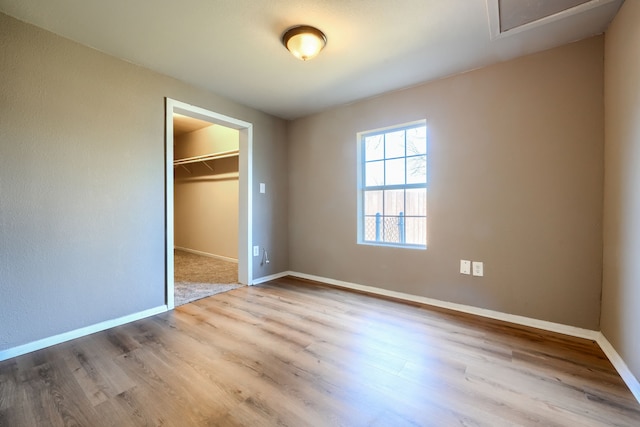 unfurnished bedroom with a walk in closet, light hardwood / wood-style floors, and a closet