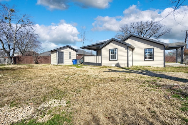 back of house with a storage unit and a lawn