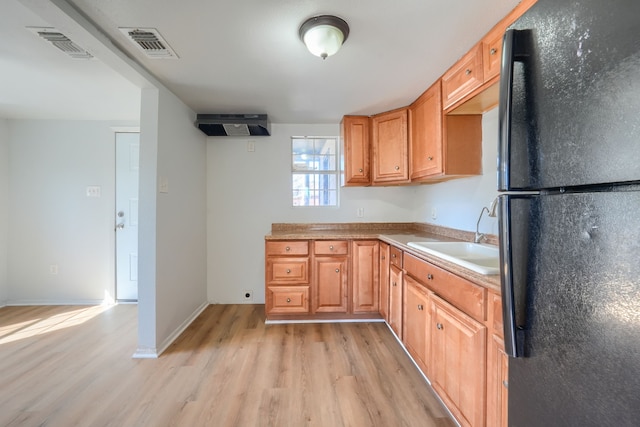 kitchen featuring sink, light hardwood / wood-style flooring, and black fridge