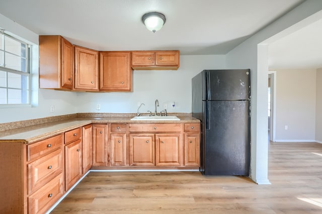 kitchen with black refrigerator, sink, and light wood-type flooring