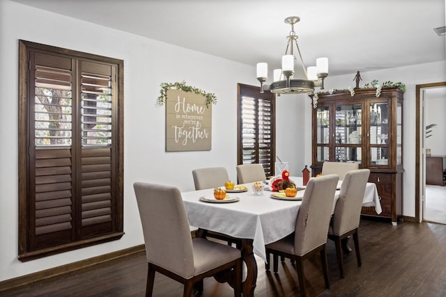 dining area featuring dark wood-type flooring and a notable chandelier