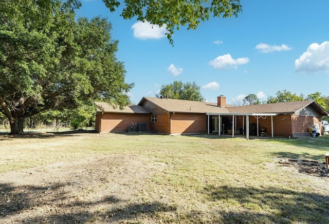 rear view of property featuring a yard and central AC