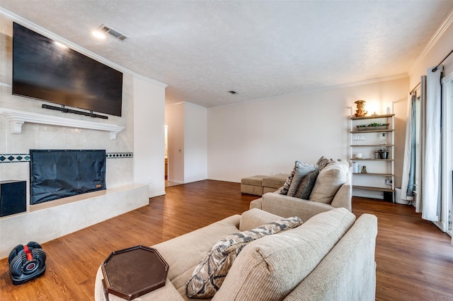 living room with wood-type flooring, a tile fireplace, and a textured ceiling