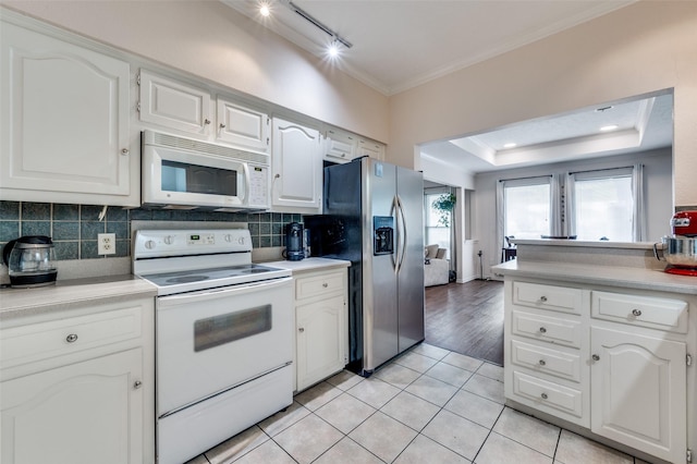 kitchen featuring light tile patterned floors, white appliances, crown molding, white cabinetry, and tasteful backsplash