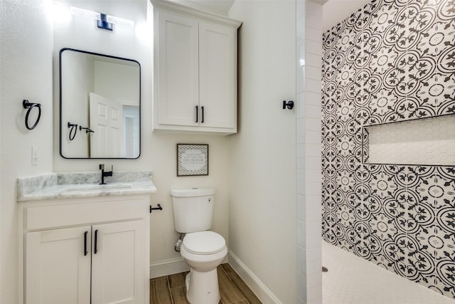 bathroom with vanity, toilet, wood-type flooring, and a tile shower