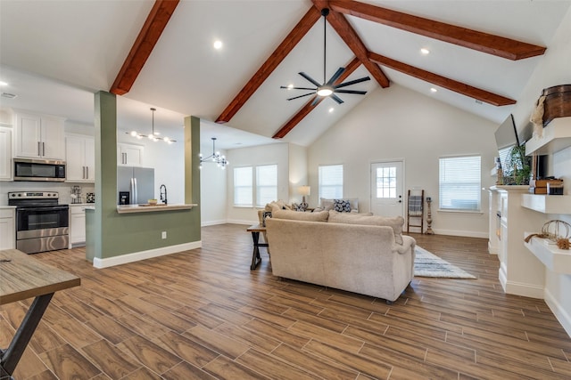 living room featuring an inviting chandelier, sink, beam ceiling, and high vaulted ceiling