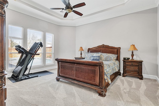 bedroom with ornamental molding, light colored carpet, ceiling fan, and a tray ceiling