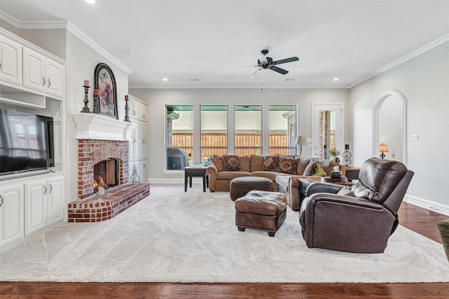 living room featuring ornamental molding, a brick fireplace, hardwood / wood-style floors, and ceiling fan