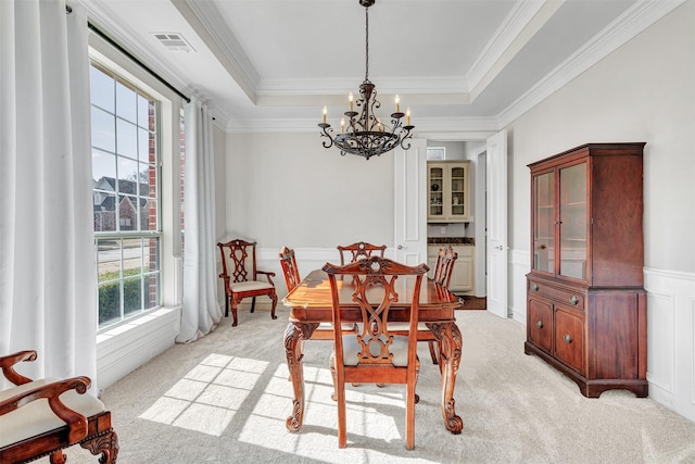 carpeted dining room featuring crown molding, a tray ceiling, and a notable chandelier