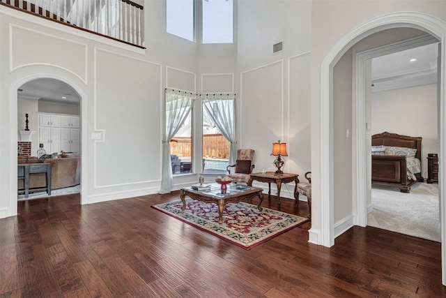 sitting room featuring a towering ceiling, ornamental molding, and dark hardwood / wood-style floors