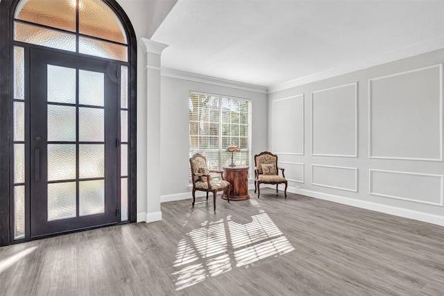 sitting room with hardwood / wood-style flooring, ornamental molding, and ornate columns