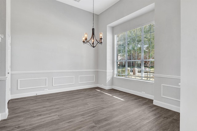 spare room with a notable chandelier and dark hardwood / wood-style floors