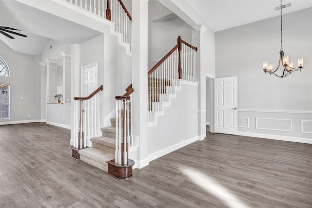 foyer entrance with hardwood / wood-style flooring, ornate columns, an inviting chandelier, and a high ceiling