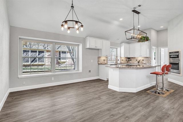 kitchen with white cabinetry, a center island, light stone counters, and hanging light fixtures