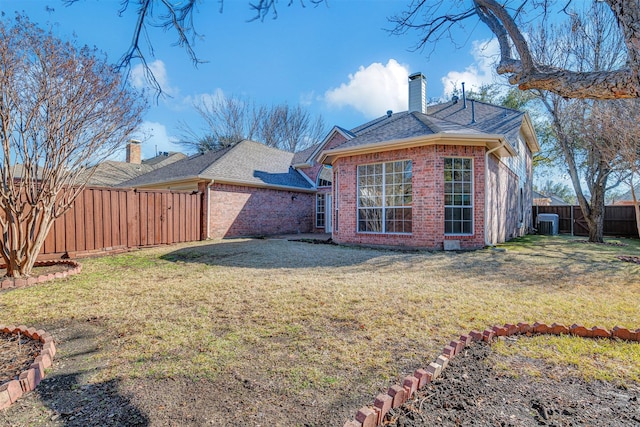 rear view of house with central AC unit and a lawn