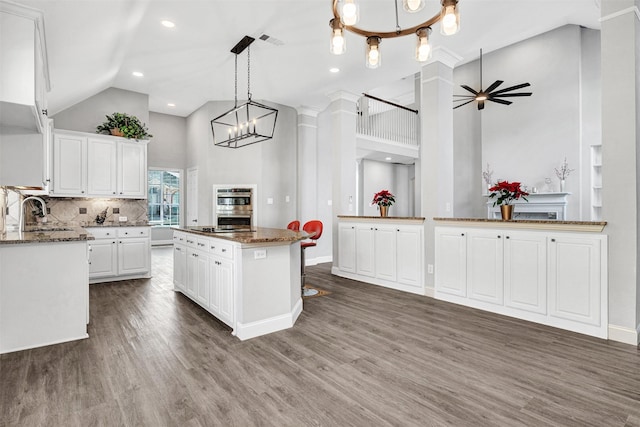 kitchen with sink, a center island, hanging light fixtures, dark hardwood / wood-style flooring, and white cabinets