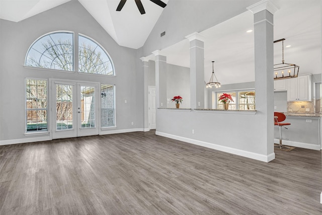 unfurnished living room with dark wood-type flooring, ceiling fan, plenty of natural light, and decorative columns